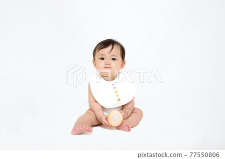 坐在白色背景上的女嬰。成長、健康、能量、育兒形象 坐在白色背景上的女嬰。成長、健康、能量、育兒形象 77550806