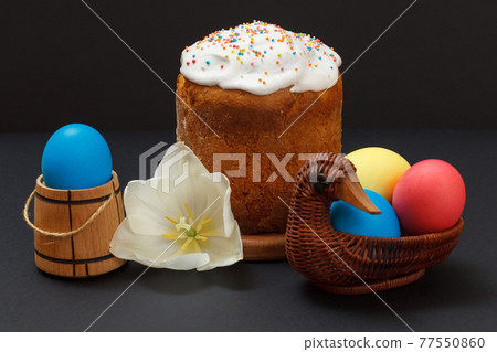 Easter cake and colorful Easter eggs in wicker basket. Easter cake and colorful Easter eggs in wicker basket. 77550860