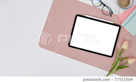 Female workplace with digital tablet, glasses, pink tulips, notebook and coffee cup. 77551084