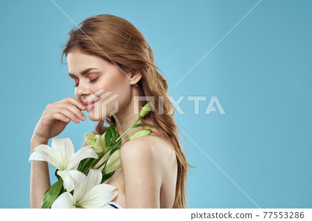 Woman with a bouquet of white flowers on a blue background naked shoulders beautiful face Woman with a bouquet of white flowers on a blue background naked shoulders beautiful face 77553286