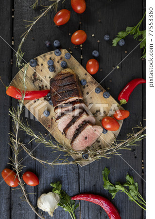 Goose breast Christmas roast with blueberries, tomatoes, red peppers and rosemary served on a wooden board Goose breast Christmas roast with blueberries, tomatoes, red peppers and rosemary served on a wooden board 77553360