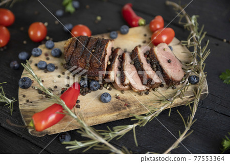 Goose breast Christmas roast with blueberries, tomatoes, red peppers and rosemary served on a wooden board Goose breast Christmas roast with blueberries, tomatoes, red peppers and rosemary served on a wooden board 77553364