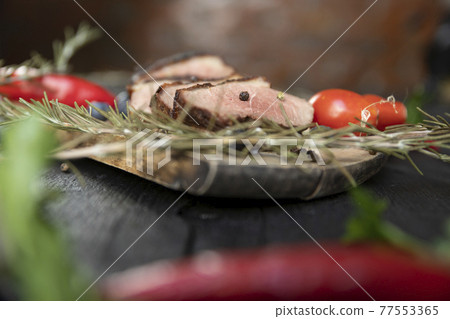 Goose breast Christmas roast with blueberries, tomatoes, red peppers and rosemary served on a wooden board Goose breast Christmas roast with blueberries, tomatoes, red peppers and rosemary served on a wooden board 77553365