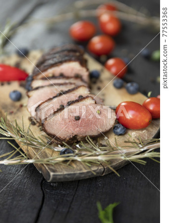 Goose breast Christmas roast with blueberries, tomatoes, red peppers and rosemary served on a wooden board Goose breast Christmas roast with blueberries, tomatoes, red peppers and rosemary served on a wooden board 77553368