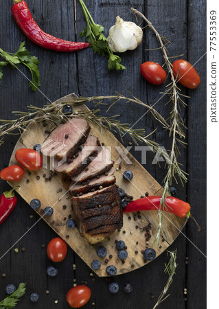 Goose breast Christmas roast with blueberries, tomatoes, red peppers and rosemary served on a wooden board Goose breast Christmas roast with blueberries, tomatoes, red peppers and rosemary served on a wooden board 77553369