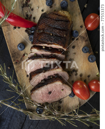Goose breast Christmas roast with blueberries, tomatoes, red peppers and rosemary served on a wooden board 77553373