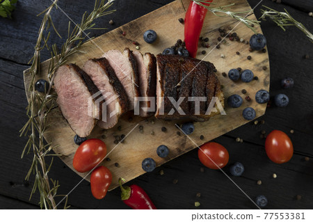 Goose breast Christmas roast with blueberries, tomatoes, red peppers and rosemary served on a wooden board Goose breast Christmas roast with blueberries, tomatoes, red peppers and rosemary served on a wooden board 77553381