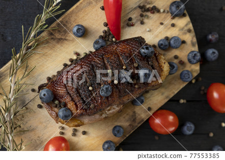 Goose breast Christmas roast with blueberries, tomatoes, red peppers and rosemary served on a wooden board Goose breast Christmas roast with blueberries, tomatoes, red peppers and rosemary served on a wooden board 77553385