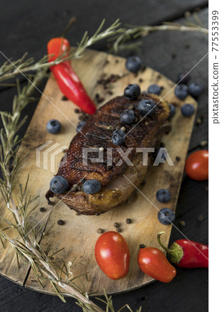 Goose breast Christmas roast with blueberries, tomatoes, red peppers and rosemary served on a wooden board Goose breast Christmas roast with blueberries, tomatoes, red peppers and rosemary served on a wooden board 77553399