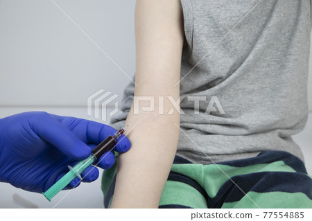 The doctor takes the boy blood from a vein. Taking blood from a child for research and laboratory analysis 77554885