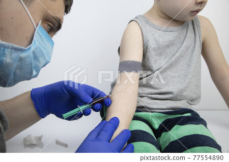 The doctor takes the boy blood from a vein. Taking blood from a child for research and laboratory analysis The doctor takes the boy blood from a vein. Taking blood from a child for research and laboratory analysis 77554890