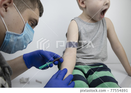 The doctor takes the boy blood from a vein. Taking blood from a child for research and laboratory analysis The doctor takes the boy blood from a vein. Taking blood from a child for research and laboratory analysis 77554891