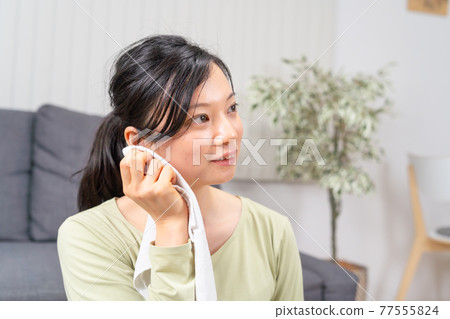 A woman who wipes sweat after exercising 77555824