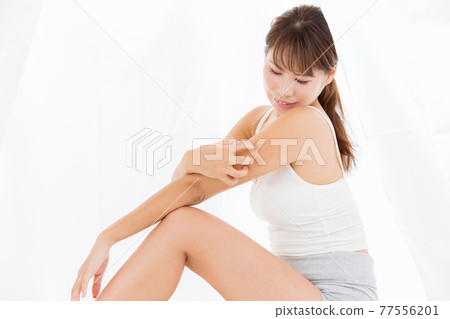 Woman scratching her arm Woman scratching her arm 77556201