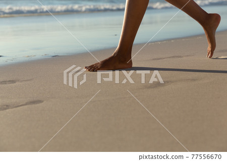 Low section of mixed race woman on beach practicing yoga durning sunset 77556670