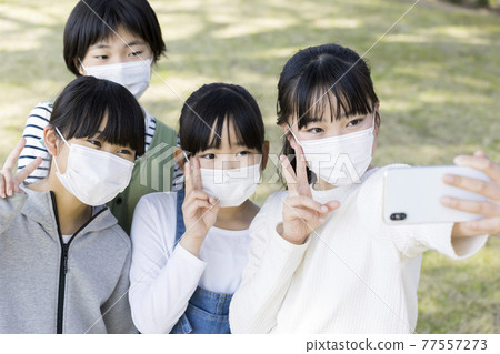 Elementary school children taking commemorative photos with their masks on 77557273