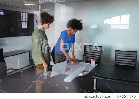 Diverse male and female colleagues in office discussing over blueprint document Diverse male and female colleagues in office discussing over blueprint document 77557479