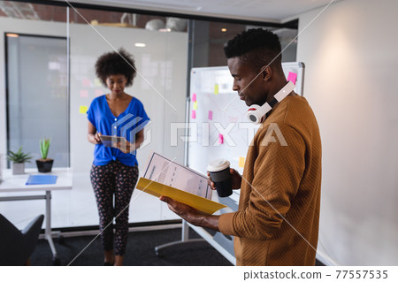 Diverse male and female colleagues standing in front of whiteboard having discussion Diverse male and female colleagues standing in front of whiteboard having discussion 77557535