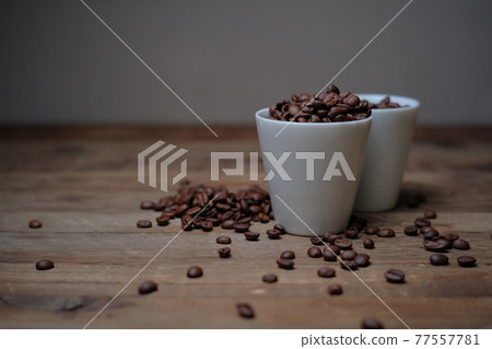 Coffee beans spilled from a cup on the table 04 77557781