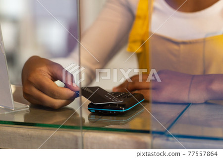 Midsection of mixed race woman paying by card Midsection of mixed race woman paying by card 77557864