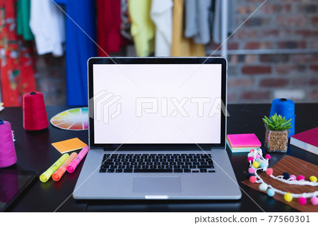 Laptop with copy space on screen lying on desk full of designers accessories 77560301