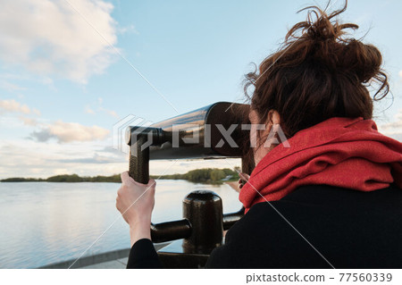 A young girl looks through a large city binoculars. City landmarks 77560339
