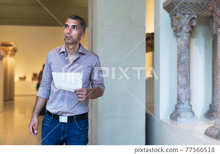 Adult man is visiting museum and looking at the exposition 77560518