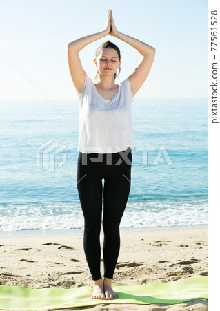 Adult female in white T-shirt is staying and practicing asana 77561528