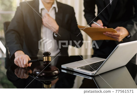 Justice and law concept. Male judge in a courtroom the gavel, working with digital tablet computer on wood table. 77561571