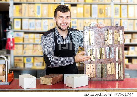 Shop assistant displaying door and furniture knobs Shop assistant displaying door and furniture knobs 77561744