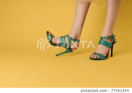 Women's legs green shoes fashionable shoes yellow background 77561924