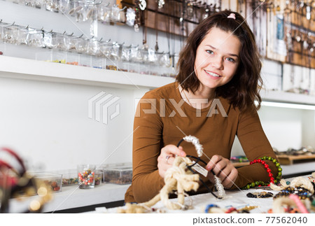 Girl seller offering colored necklaces and pendants 77562040