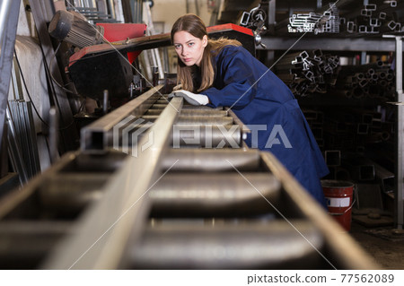Workwoman inspecting steel stocks in workshop 77562089