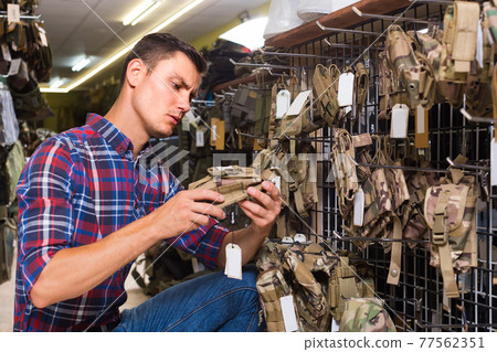 guy looking holster for pneumatic weapon in army store guy looking holster for pneumatic weapon in army store 77562351
