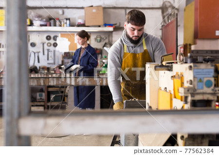 Portrait of man working with drilling machine on metal plate Portrait of man working with drilling machine on metal plate 77562384