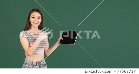 Young Caucasian woman using digital tablet isolated on green background. Young Caucasian woman using digital tablet isolated on green background. 77562717