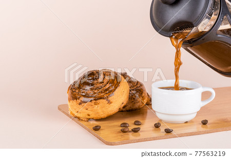Pouring black coffee into a white cup. Pouring black coffee into a white cup. 77563219