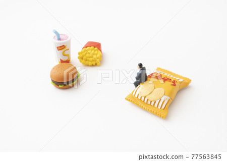 Businessman sitting in miniature fast food and snacks Businessman sitting in miniature fast food and snacks 77563845