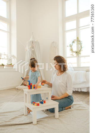 A young mother spends time with her little daughter at home. A young mother spends time with her little daughter at home. 77565160