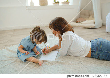 A young mother spends time with her little daughter at home. A young mother spends time with her little daughter at home. 77565164