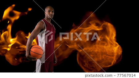 Composition of basketball player holding basketball over flames Composition of basketball player holding basketball over flames 77567014