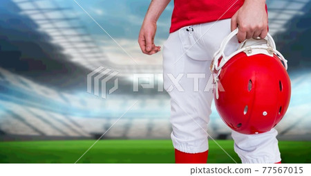 Composition of midsection of male american football player holding red helmet in sports stadium Composition of midsection of male american football player holding red helmet in sports stadium 77567015