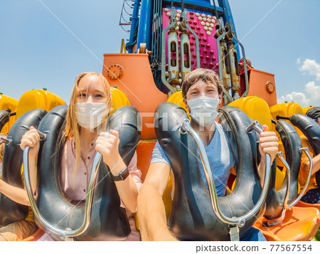 Family wearing a medical mask during COVID-19 coronavirus at an amusement park 77567554