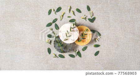 Three round natural handmade soaps with the twigs of eucalyptus on the cotton background. Zero waste concept of bathing without any package and only with natural ingredients. Three round natural handmade soaps with the twigs of eucalyptus on the cotton background. Zero waste concept of bathing without any package and only with natural ingredients. 77568903