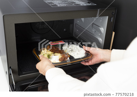 一個女人的手用微波爐加熱便利店的午餐 77570218