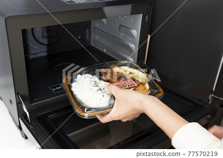 一個女人的手用微波爐加熱便利店的午餐 77570219