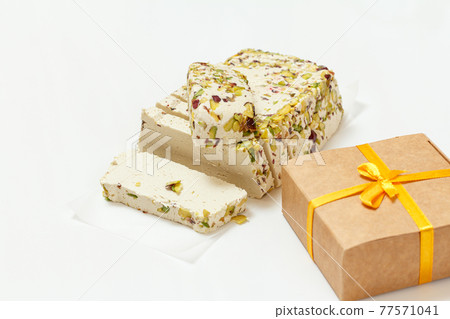Halva with pistachios and gift box on white background Halva with pistachios and gift box on white background 77571041