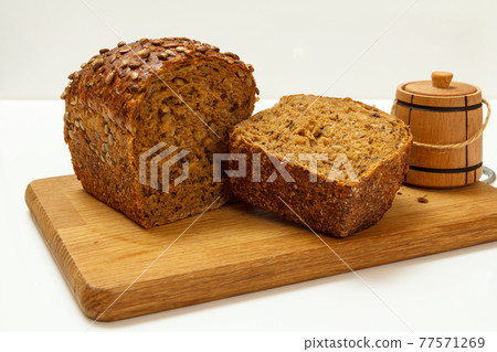 Cut loaf of bread on wooden cutting board on white background 77571269
