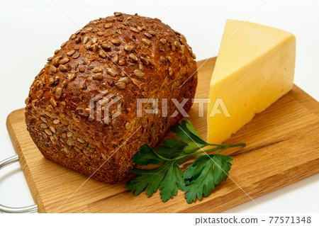 Loaf of bread and cheese on wooden cutting board on white background 77571348
