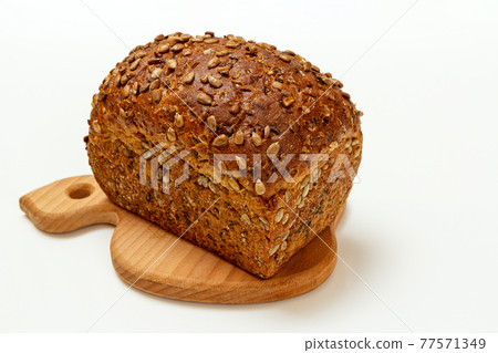 Loaf of bread on wooden cutting board on white background 77571349